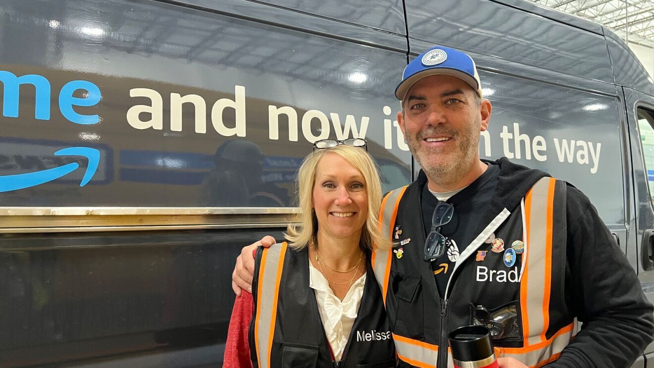 An image of a woman, an Amazon Delivery Service Partner, in a work vest standing in front of a delivery van.