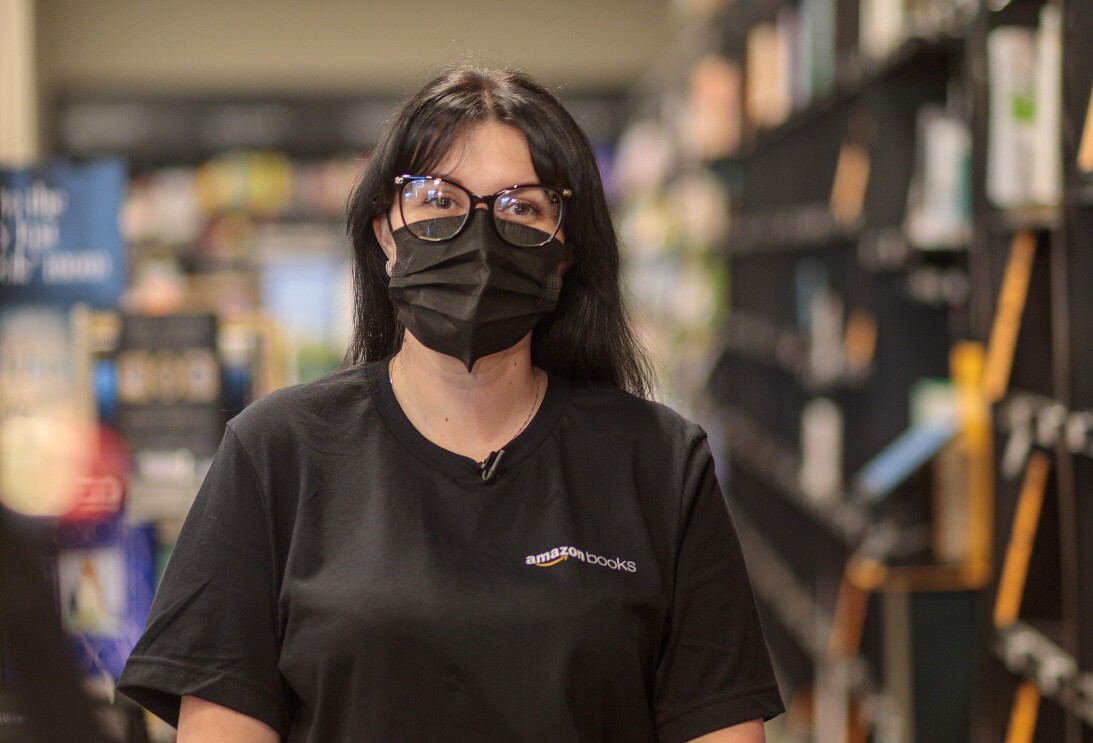 An image of a woman standing in an Amazon bookstore smiling for a photo under her mask.