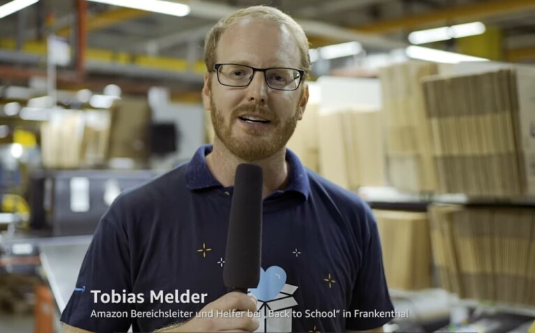 Ein Mann im Amazon T-Shirt, der ein Mikro in der Hand hält.