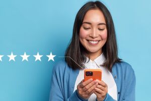 Five-star review concept with smiling woman holding orange smartphone