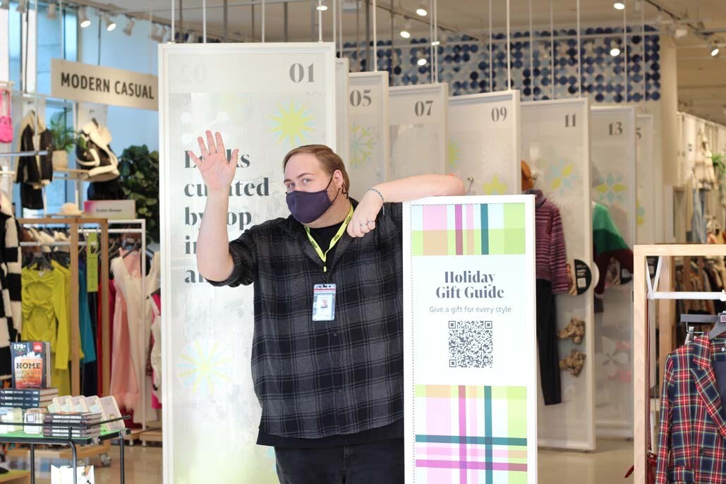 An image of an Amazon Style store employee waving at the camera in the entryway of the store.