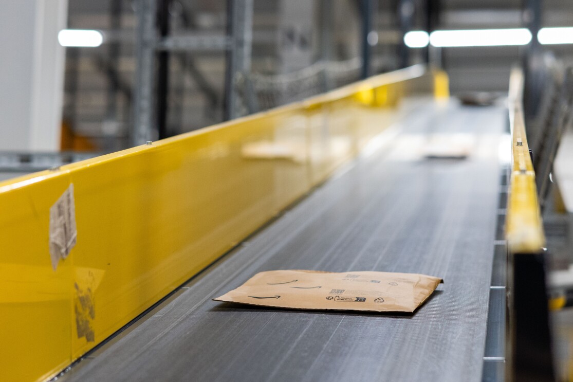 A conveyor belt carrying cardboard packaging in an Amazon fulfilment centre