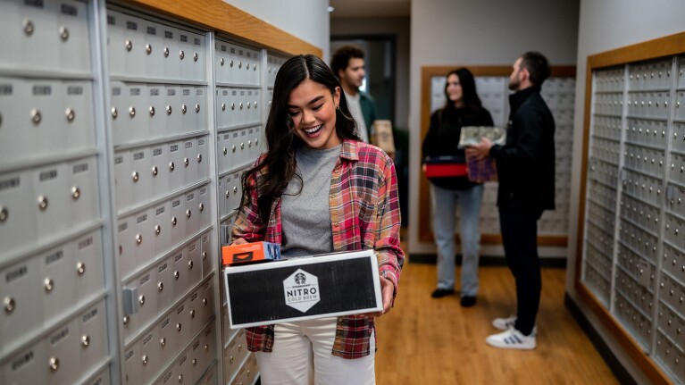 An image of a woman holding a package in a mailroom. 