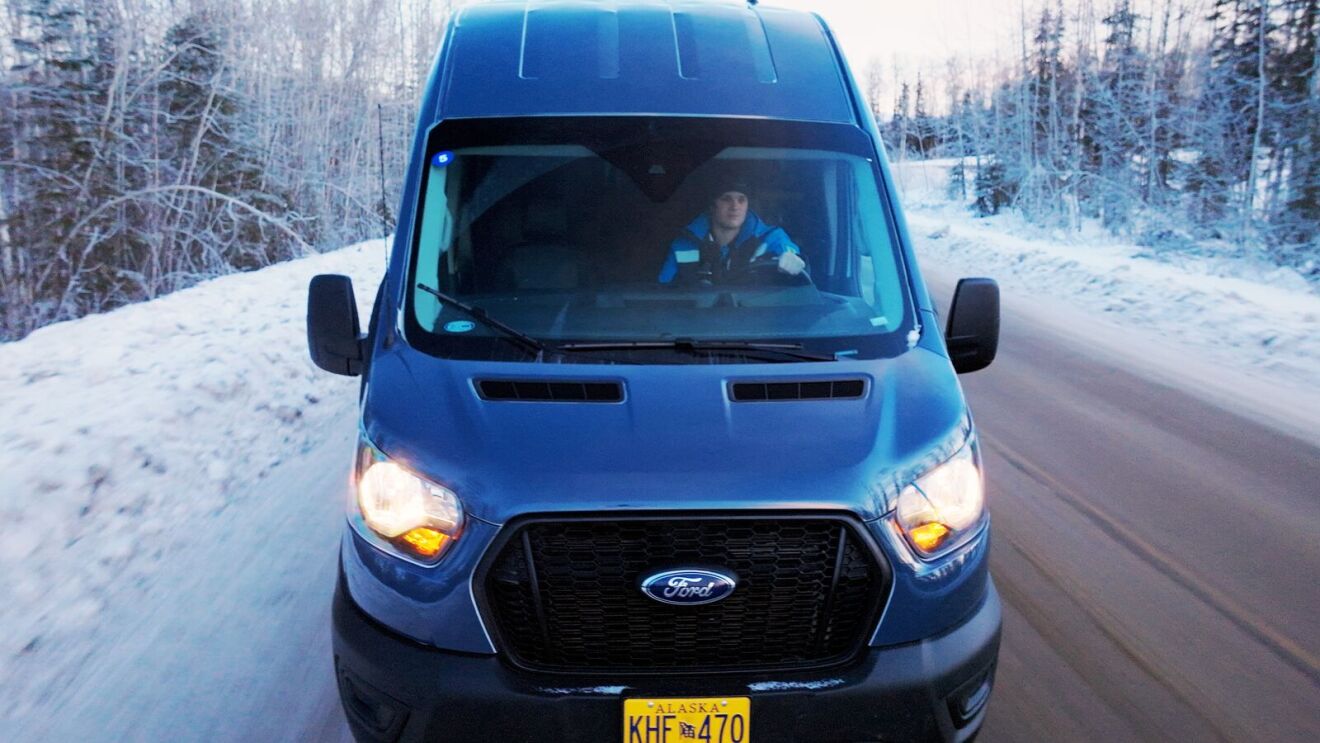 Amazon delivery vehicle navigating icy Alaskan highway in winter
