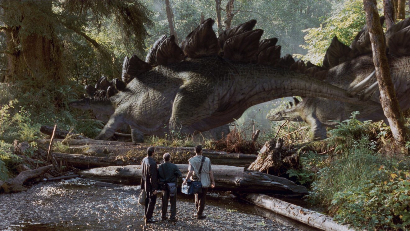 Cinematic recreation of humans encountering a stegosaurus in ancient woodland.