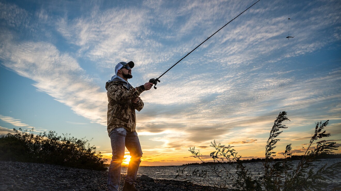 一个人沿着一条河钓鱼的照片。
