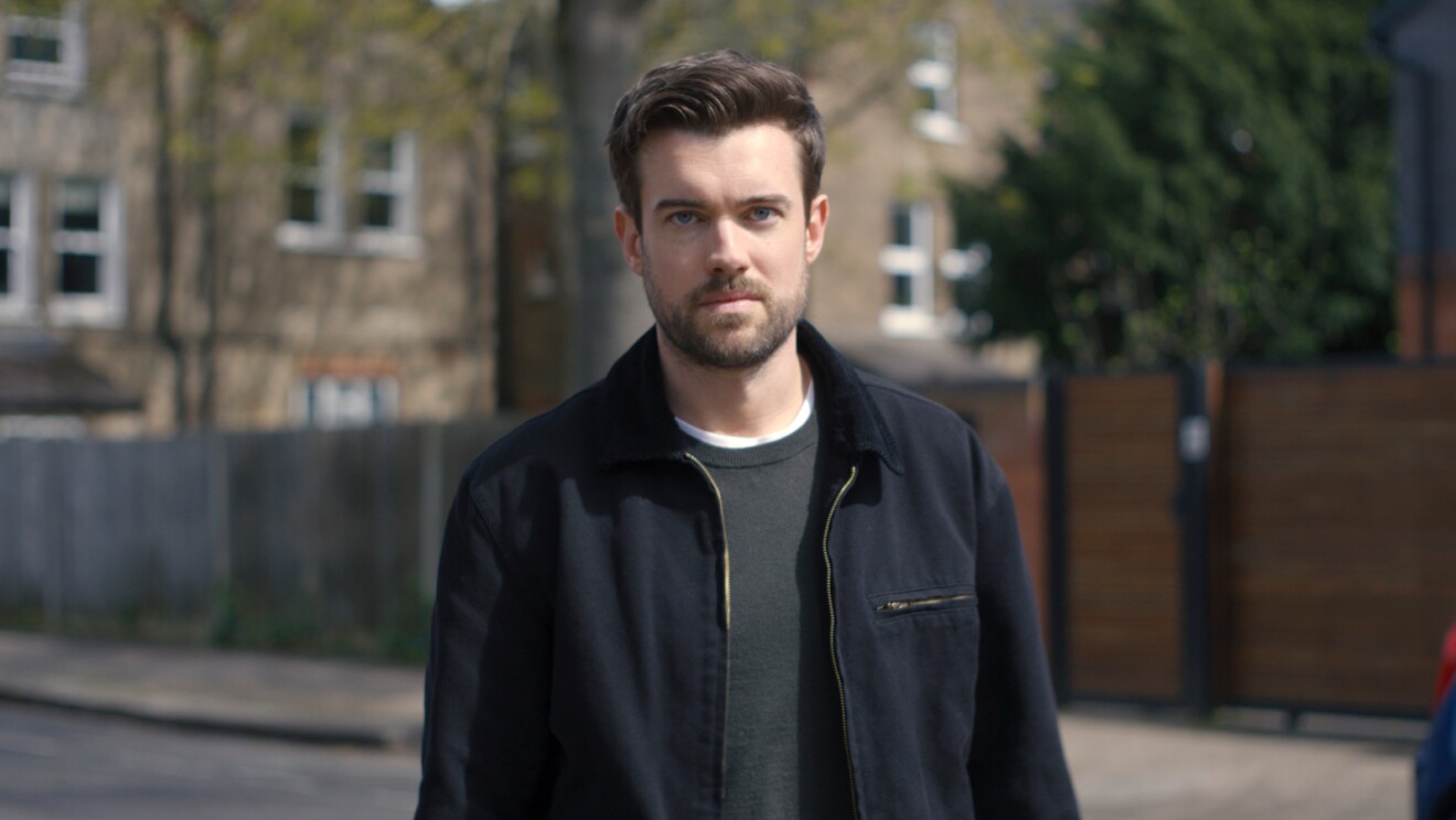 Man in black jacket standing on urban street
