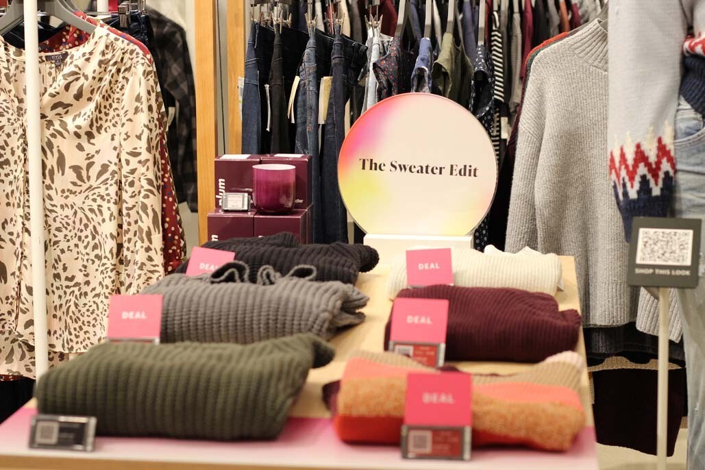 A display of sweaters at the Amazon Style store with a sign that reads "The Sweater Edit."