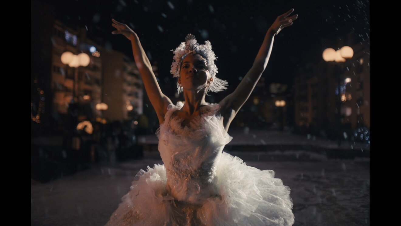 Ballerina dressed in white feathers and arms in the air 