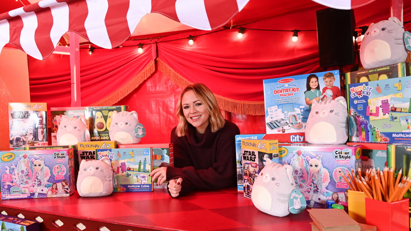 A woman at her toy stand, surrounded by toy boxes and teddies