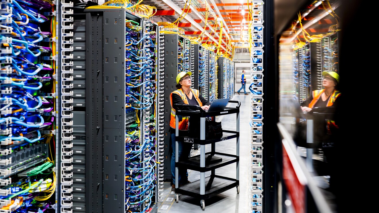Modern server room with workers maintaining complex network infrastructure for data centers