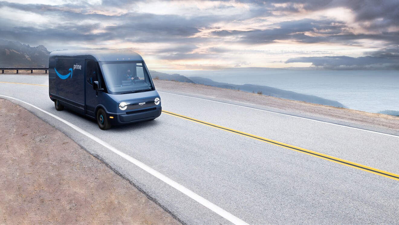 An image of a Rivian van with the Amazon Prime logo driving on a coastline highway.  