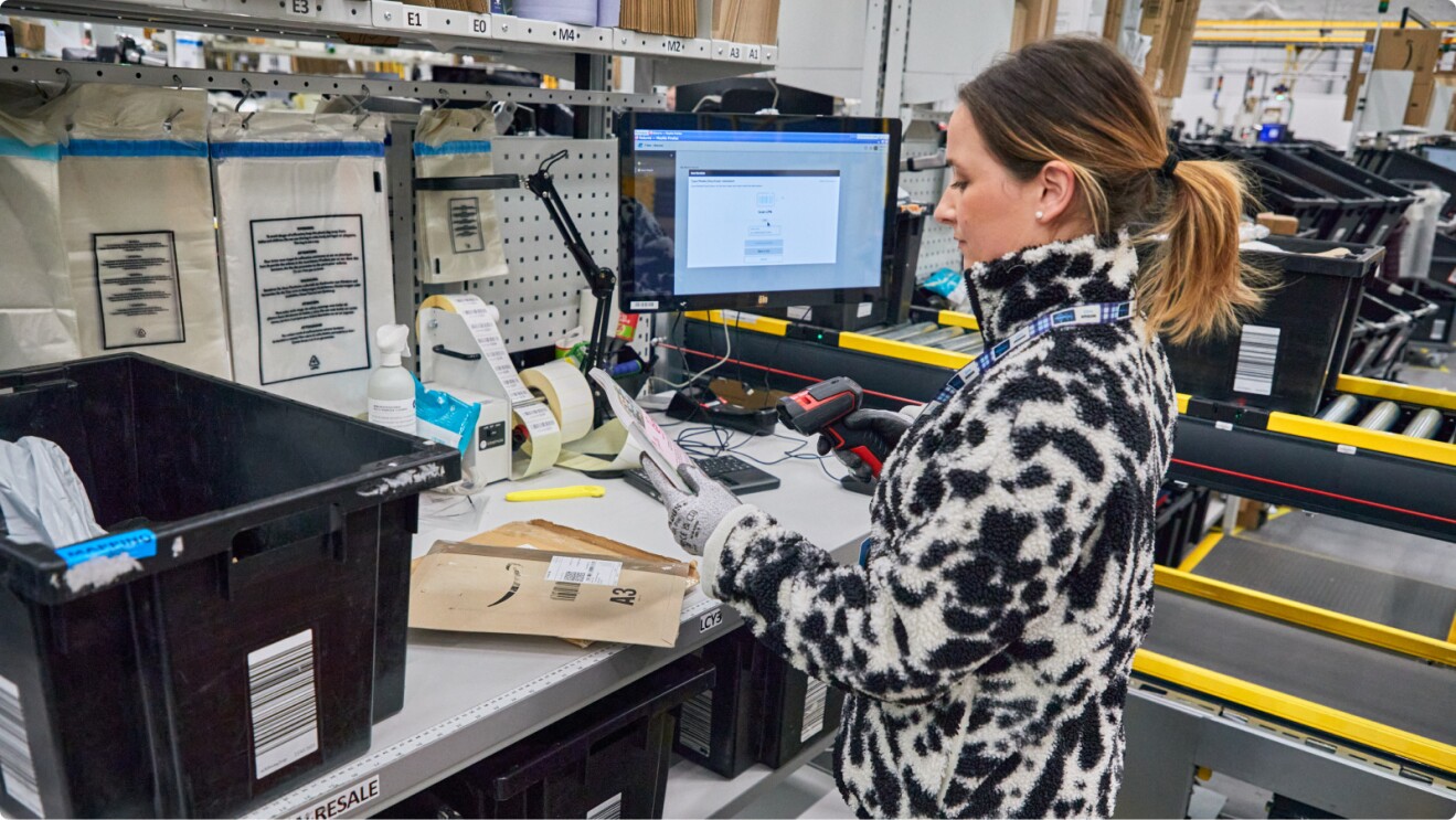 Worker in leopard print jacket processing returns at Amazon warehouse station