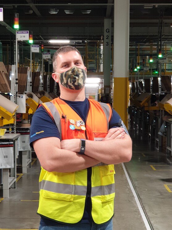 Igor Franciskovity, Area Manager at Amazon's fulfilment centre in Tilbury pictured cross-armed and wearing a high visibility vest and mask, with the shop-floor in the background.