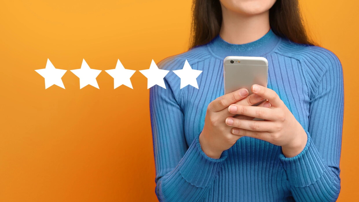 Torno de una mujer mirando el teléfono con 5 estrellas de color blanco. El fondo es naranja. 