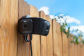 Blink security camera mounted on wooden fence under blue sky
