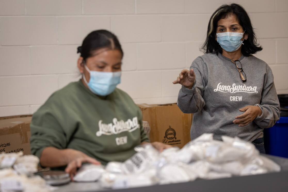 Two women wearing masks and sweatshirts that say "Luna Sundara crew."
