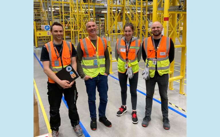 An image of Stefano Perego working with employees at an amazon facility.