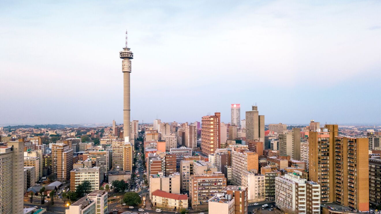 Johannesburg city skyline at dusk with the iconic Hillbrow Tower rising above residential and commercial buildings