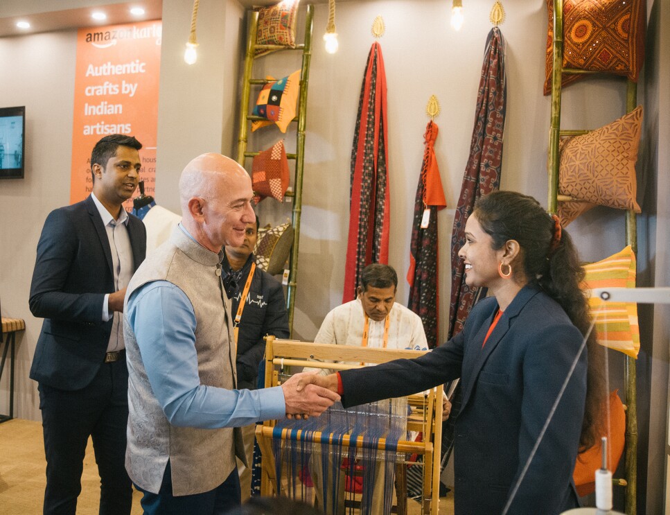 Jeff Bezos shakes the hand of a woman artisan and small business owner. 