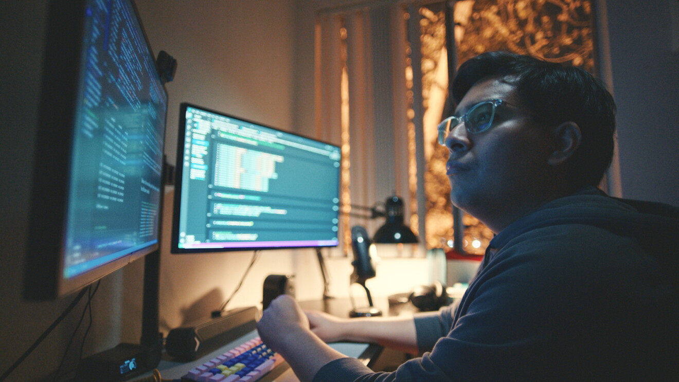 José Tapia, sitting at a desk, viewing information on two computer monitors.