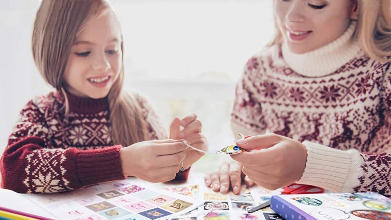 A child and young woman work together on a craft. Images are strewn across the tabletop as part of the craft kit.