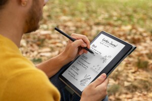 An image of a person wearing a yellow shirt writing on the Kindle Scribe. 