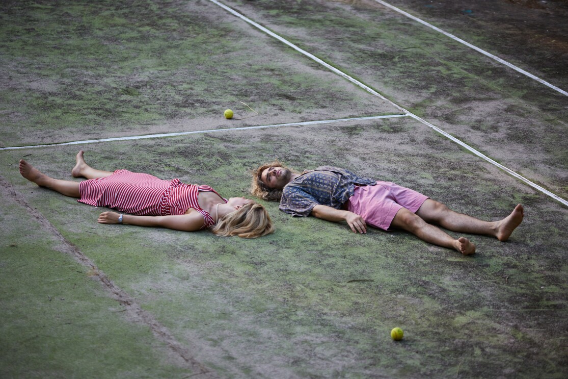 Szene aus Perfect Match, der Geschichte über Steffi Graf und Andre Agassi. Steffi Graf (Lena Klenka) und Andre Agassi (Toby Sebastian) liegen auf dem Boden eines Tennisfelds auf dem Rücken und sehen sich an.