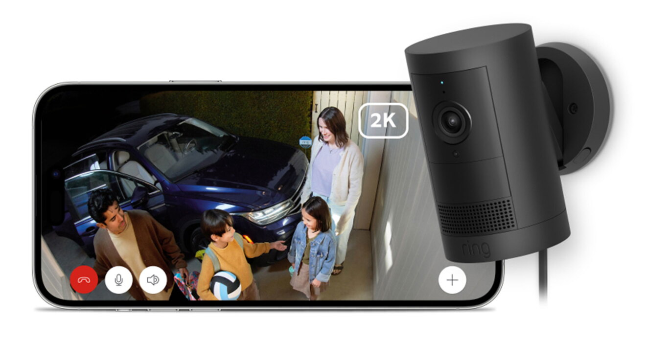 右側に黒のセキュリティカメラと、左側にスマートホン。スマホは横長に置かれ、画面にはカメラの捉えた映像が映っている。映像では、車から降りて玄関口に立つ大人2人と子ども2人が見える。