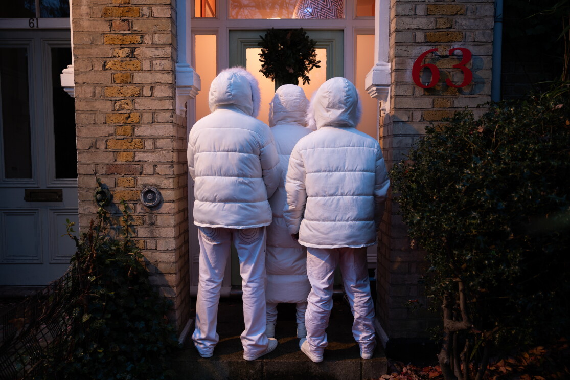 East 17 Band is standing on the doorstep of a christmas decorated home. 