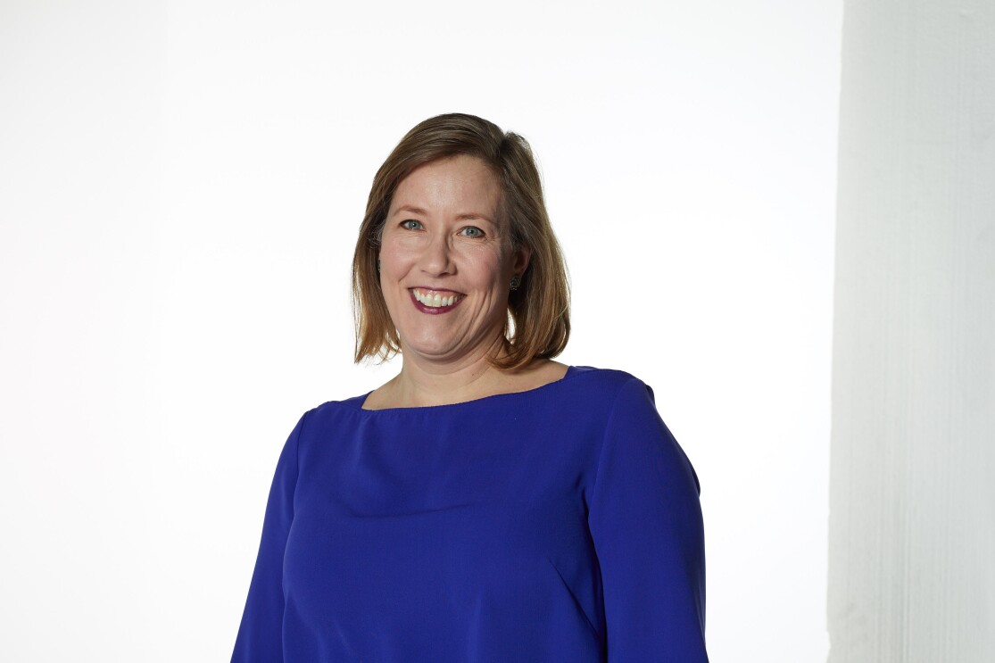 Female wearing a blue jumper smiling directly at the camera 