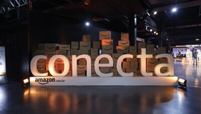 Uma placa da Amazon Brasil conecta em frente a diversas caixas com o símbolo da Amazon