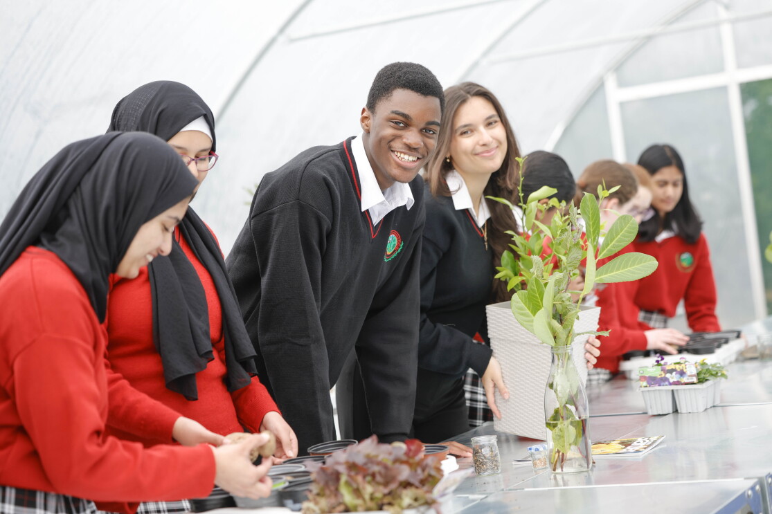 Students at AWS in communities event pose for photo at their gardening project station