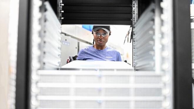 员工工作的照片前面的服务器机架在AWS数据中心。