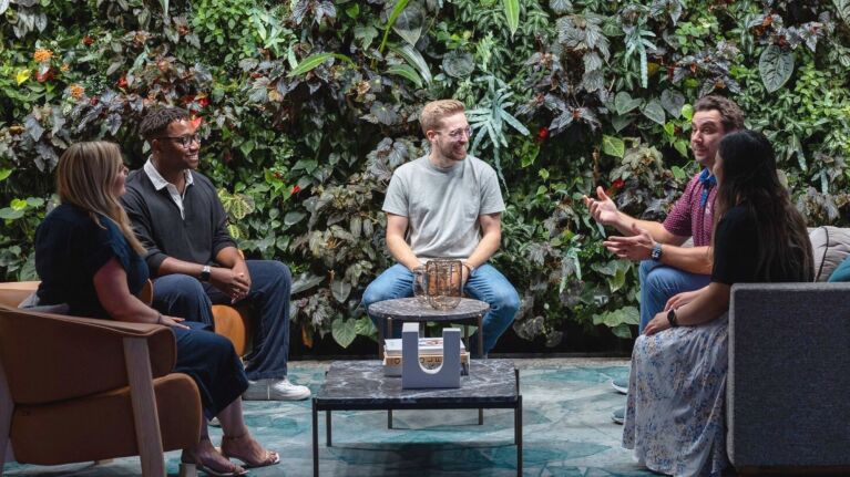 Employees engaged in discussion amidst a backdrop of plants