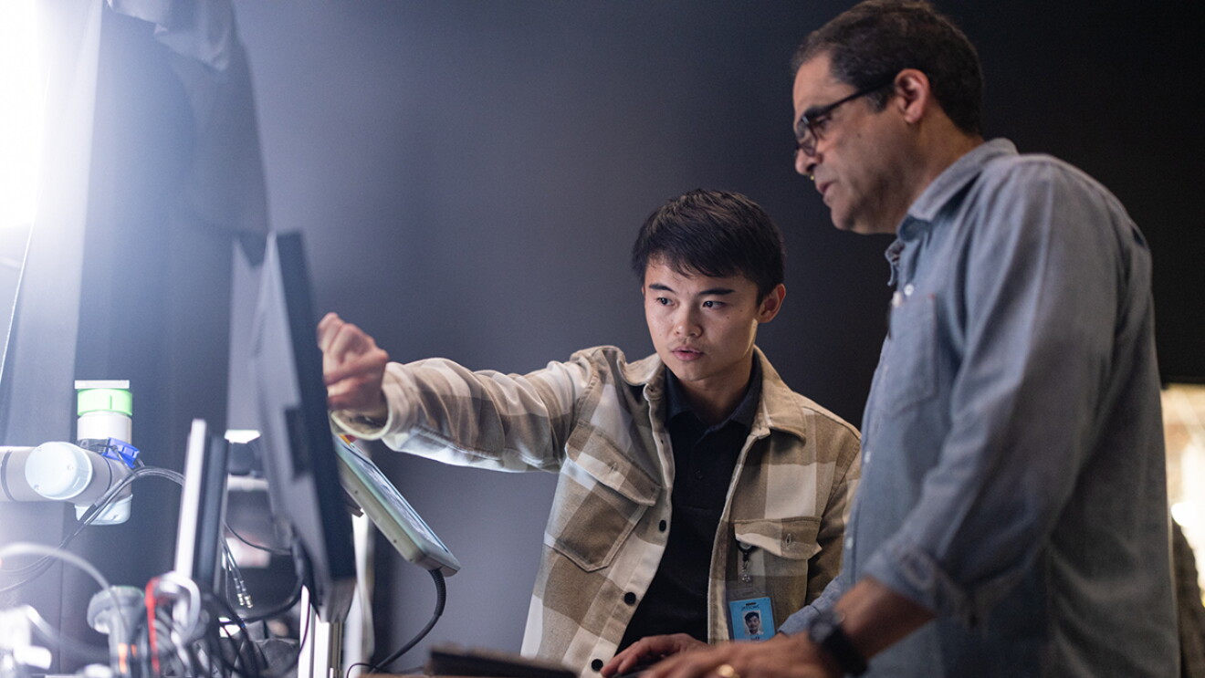 Prime Air employees at a R&D facility work together at computer screens.