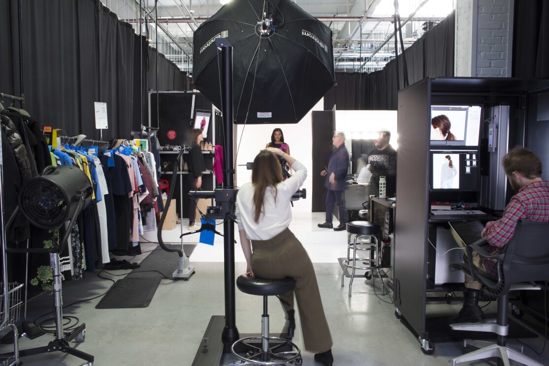 An Amazon Fashion photographer, in a white shirt and brown slacks, photographs a model at Amazon Fashion's studios.