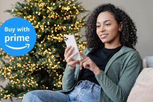Woman using smartphone by Christmas tree with Amazon Buy with Prime logo