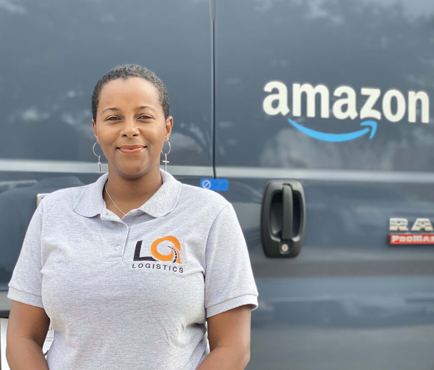 Amazon Delivery Service Partner Quanique Toston stands in front of an Amazon delivery van.