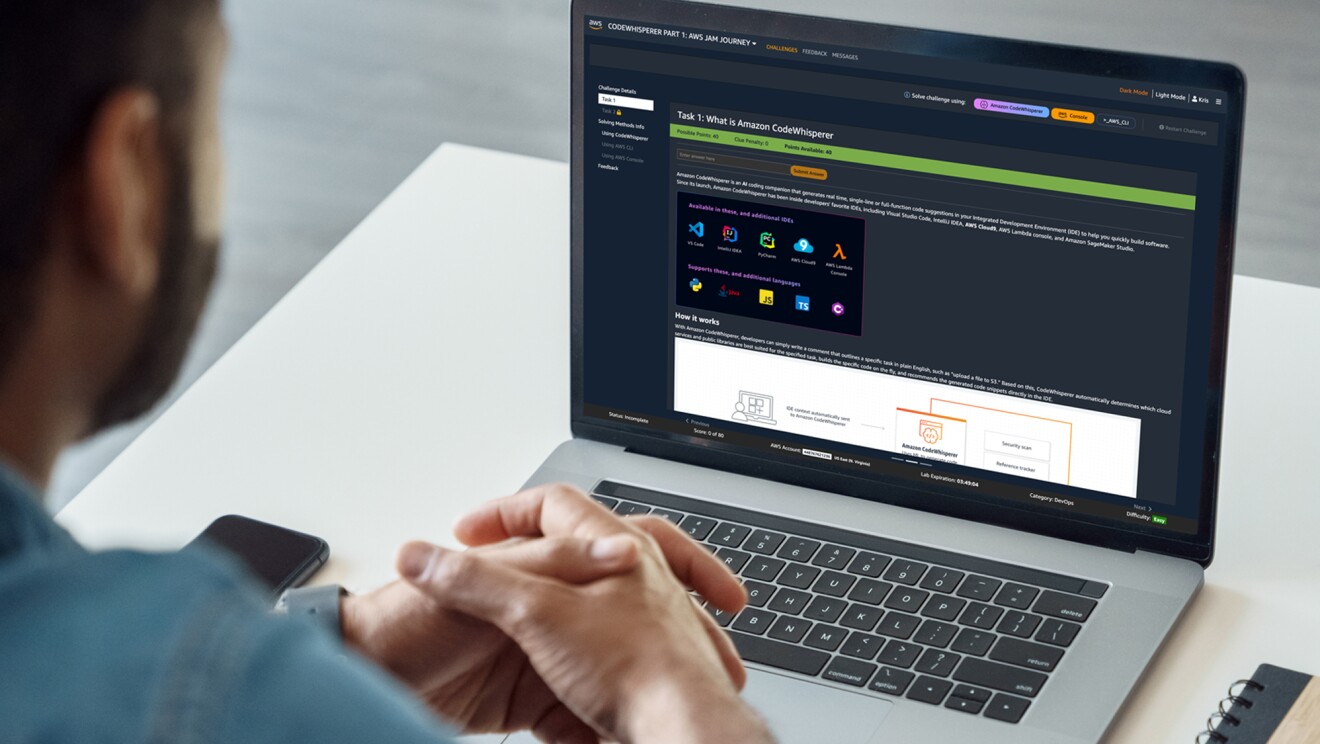 A photo of a person looking at a laptop device. Operating on that device is the AWS "Amazon CodeWhisperer – Getting Started" course.
