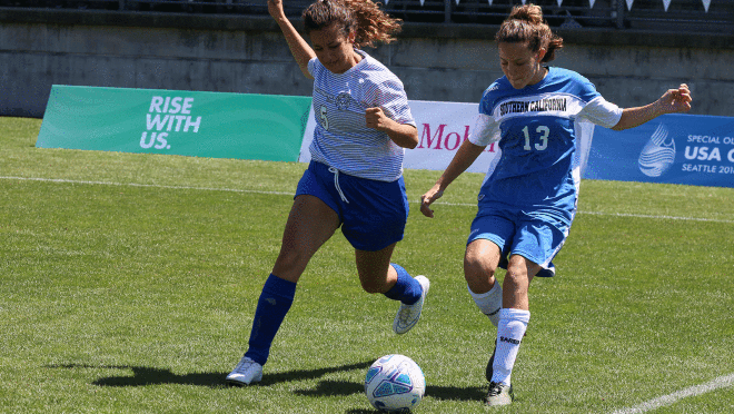 的形象运行两个足球运动员在足球场上踢球在特殊奥运会。右边的人穿着一件衬衫,说“南加州。”