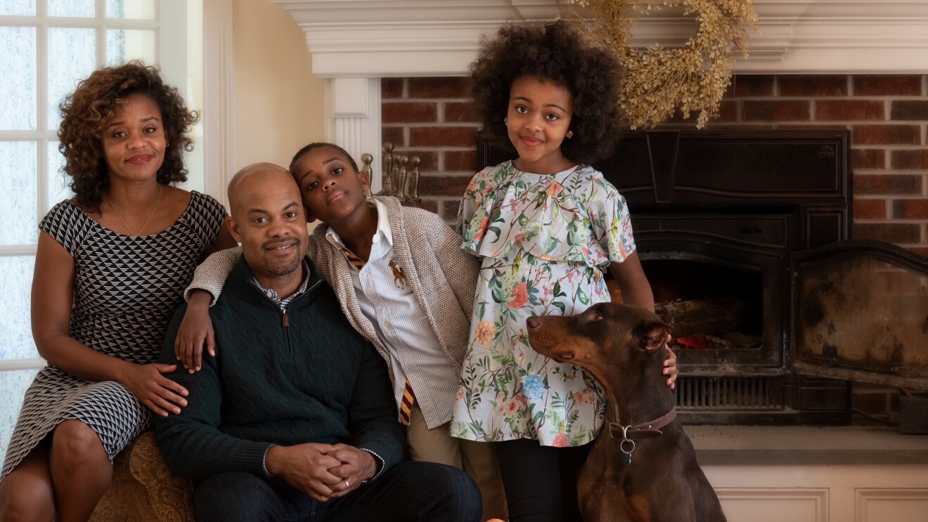 A family smiling for a photo in a living room.