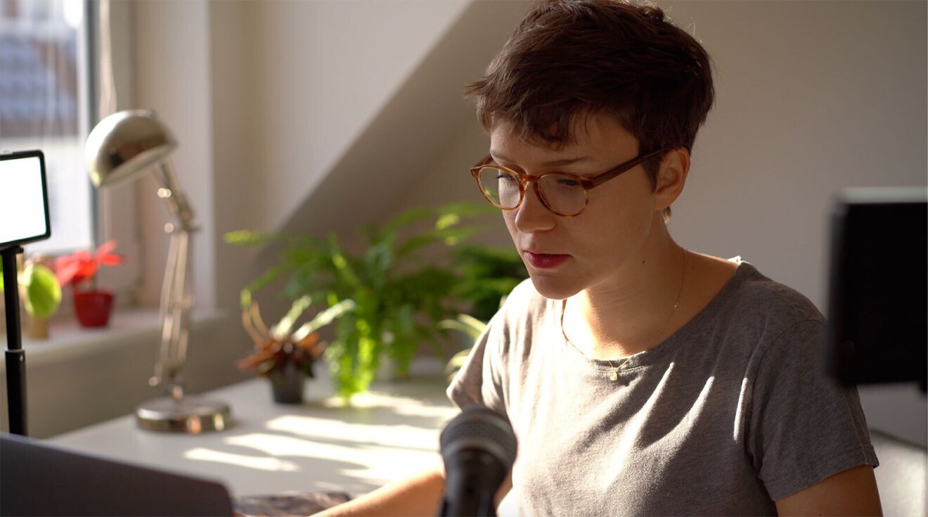 A professional image of Antonia sitting at a desk looking at her laptop while working.