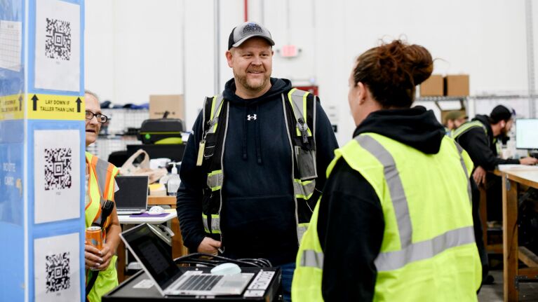 Employees in safety vests having a conversation in warehouse