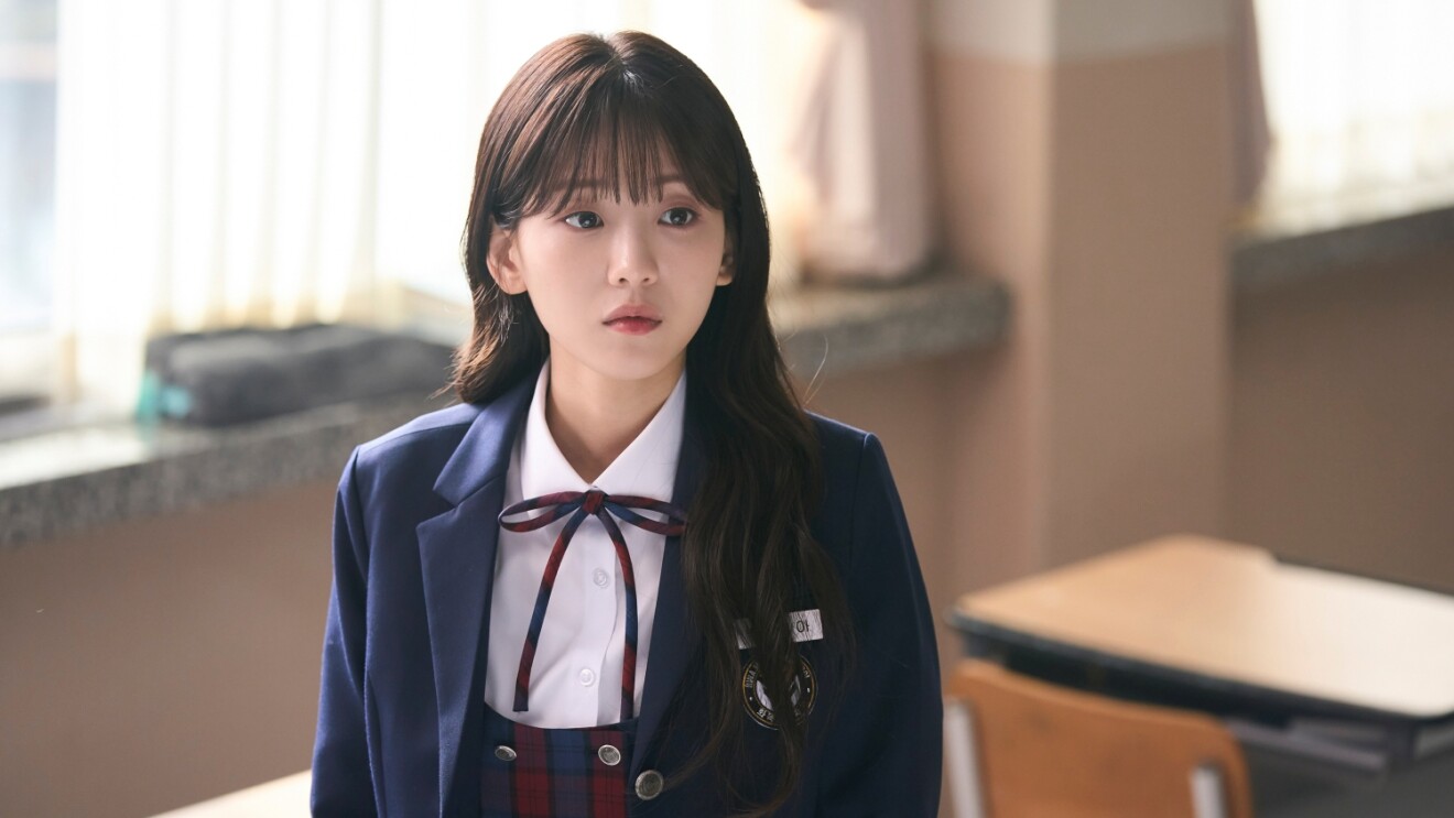 Young woman in school uniform looking pensive in classroom