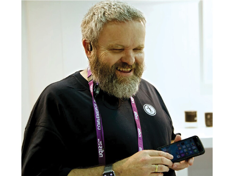 David, smiling and holding a smartphone.