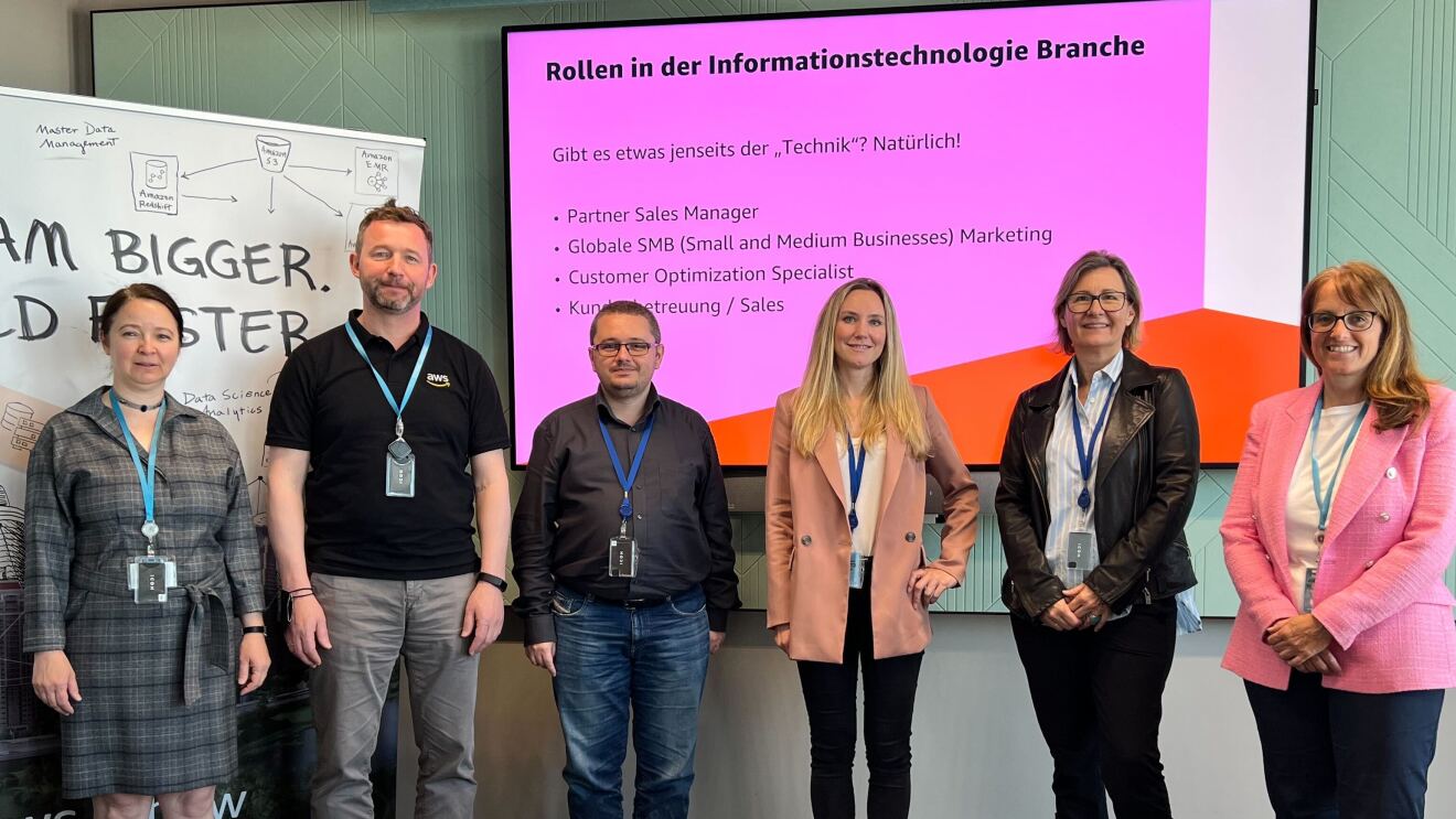 Gruppenbild des Teams von AWS beim Wiener Töchtertag 2022 vor einem Plakat mit der Aufschrift "Dream bigger. Build faster" und einer Leinwand mit der Aufschrift "Rollen in der Informationstechnologie Branche". Zu sehen sind Agnes Balaz, Alex Matai, Andreas Juffinger, Petra Wolf, Hildegard Kerschbaumer und Nina Michor.