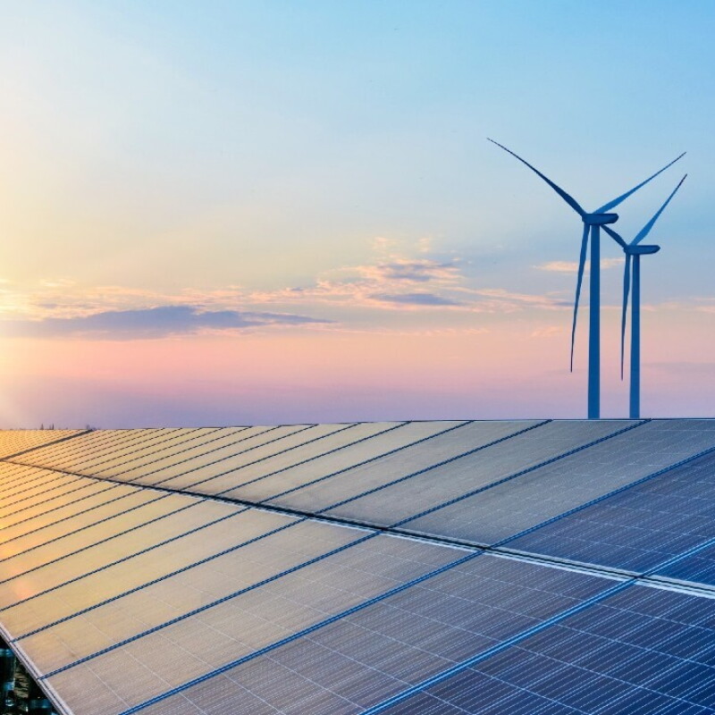 The sun sets on a wind and solar panel farm.
