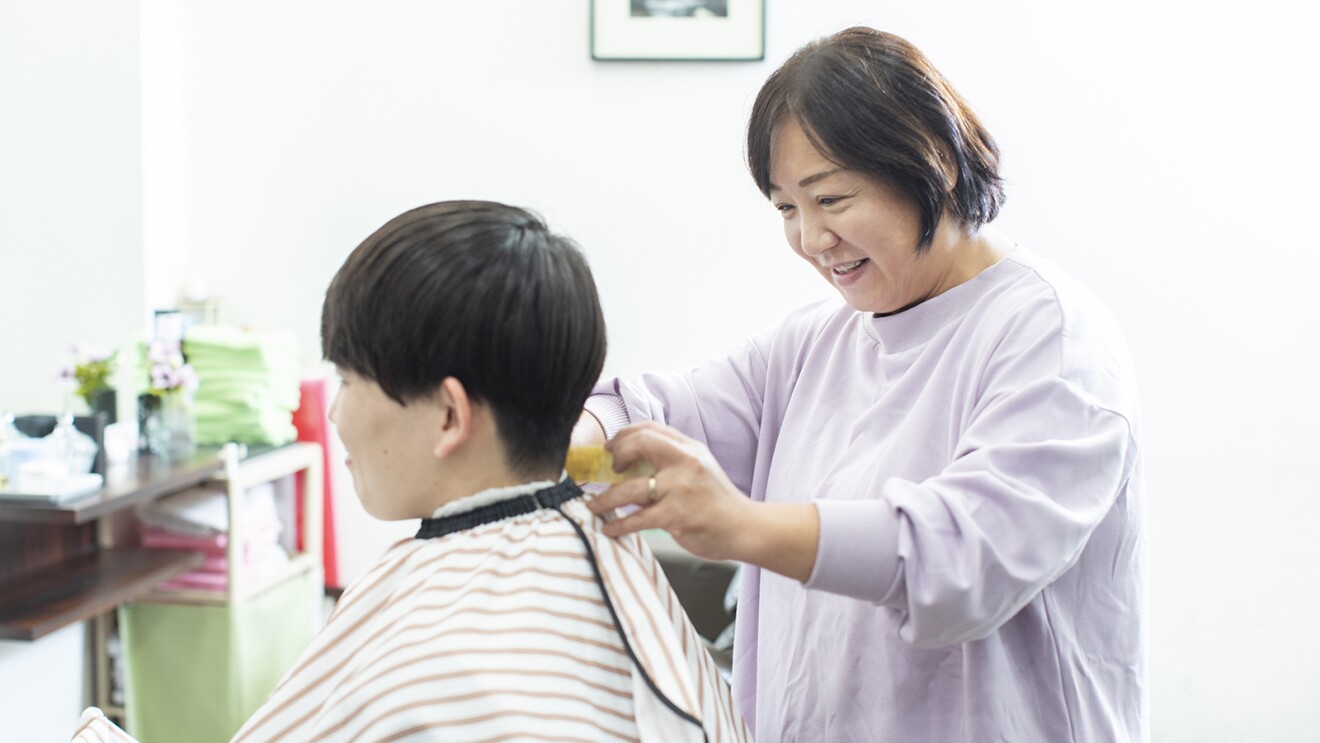 理容店でお客様にケープを巻く女性