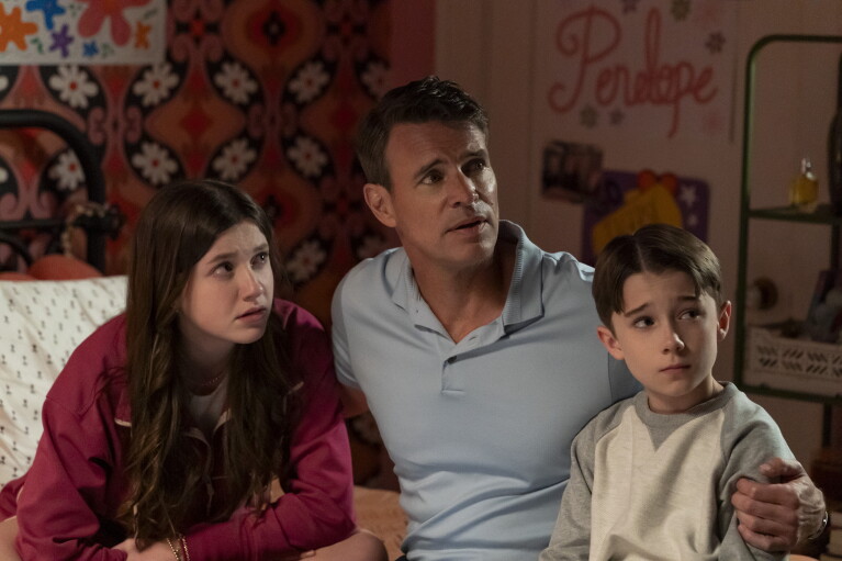 Father sits between his young daughter and son in a children's bedroom 